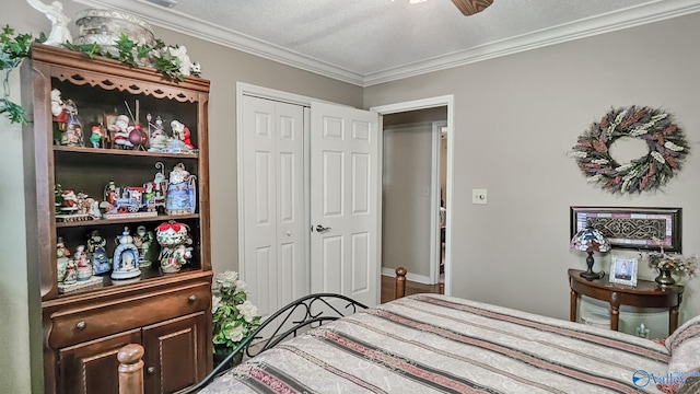 bedroom with a closet, ornamental molding, ceiling fan, a textured ceiling, and baseboards