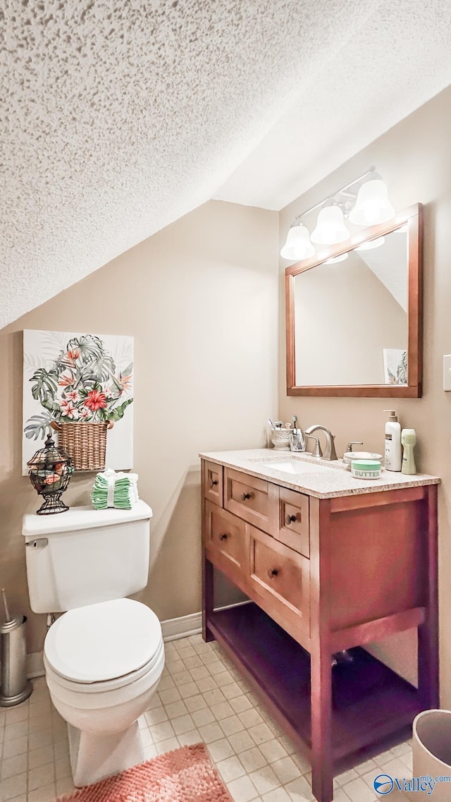 bathroom featuring lofted ceiling, a textured ceiling, tile patterned flooring, toilet, and vanity