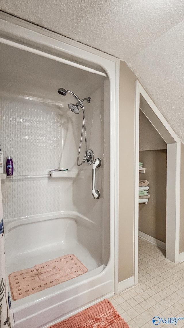 full bathroom with lofted ceiling, a shower, a textured ceiling, and tile patterned floors