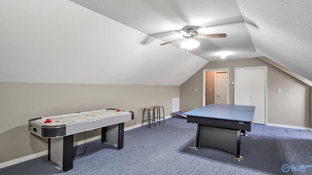 recreation room with lofted ceiling, dark carpet, a textured ceiling, and baseboards