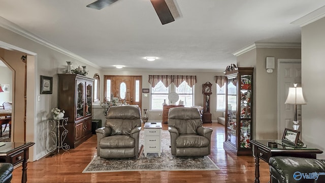 living area with baseboards, wood finished floors, and crown molding