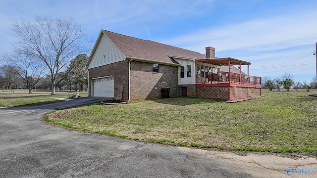 view of property exterior with driveway, a chimney, a lawn, and brick siding