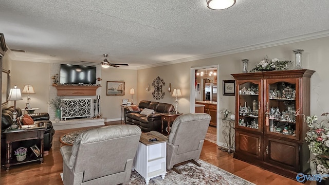 living area featuring ornamental molding, dark wood-style flooring, a large fireplace, and a textured ceiling