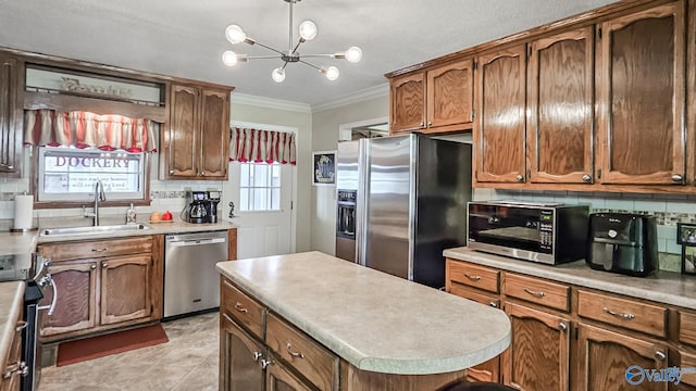 kitchen featuring brown cabinetry, appliances with stainless steel finishes, ornamental molding, light countertops, and a sink