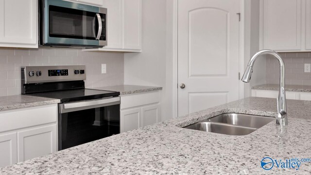 kitchen with a sink, tasteful backsplash, appliances with stainless steel finishes, and white cabinets
