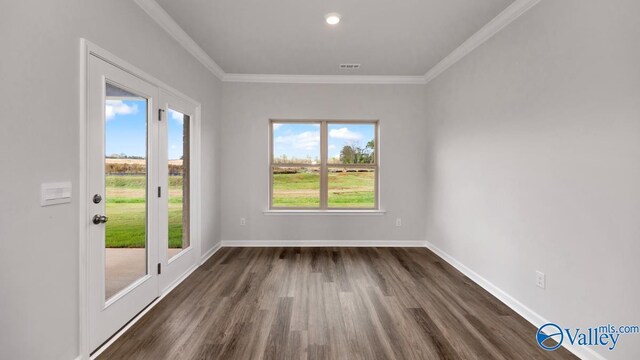 spare room featuring visible vents, crown molding, baseboards, and dark wood finished floors
