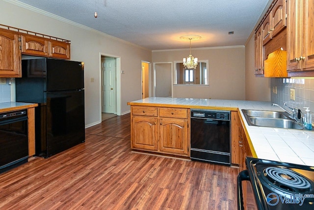 kitchen with tile countertops, dark wood-style floors, a peninsula, black appliances, and a sink