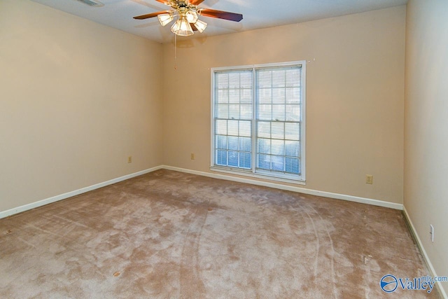 carpeted empty room featuring ceiling fan, visible vents, and baseboards