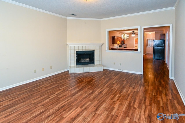 unfurnished living room featuring a textured ceiling, baseboards, dark wood-style floors, a tiled fireplace, and crown molding