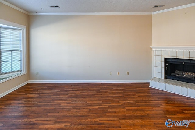 unfurnished living room with ornamental molding, visible vents, a fireplace, and wood finished floors