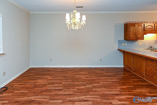 unfurnished dining area featuring dark wood-style flooring, visible vents, crown molding, and a notable chandelier