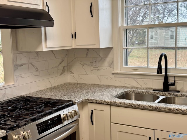 kitchen with white cabinets, sink, stainless steel stove, light stone countertops, and tasteful backsplash