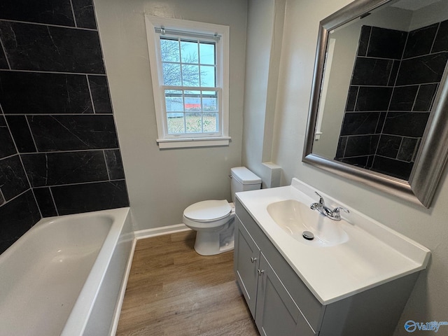 full bathroom with hardwood / wood-style floors, vanity, toilet, and tiled shower / bath