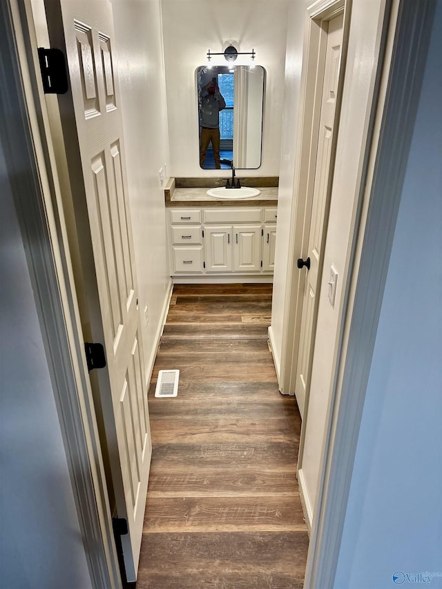 corridor with dark hardwood / wood-style flooring and sink