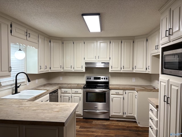 kitchen with appliances with stainless steel finishes, backsplash, sink, dark hardwood / wood-style floors, and white cabinetry