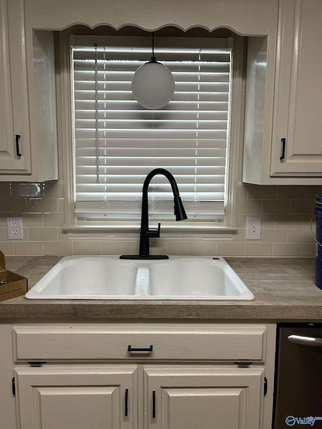 details featuring decorative backsplash, white cabinetry, and sink