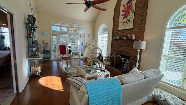 living room with ceiling fan, vaulted ceiling, a brick fireplace, and a wealth of natural light