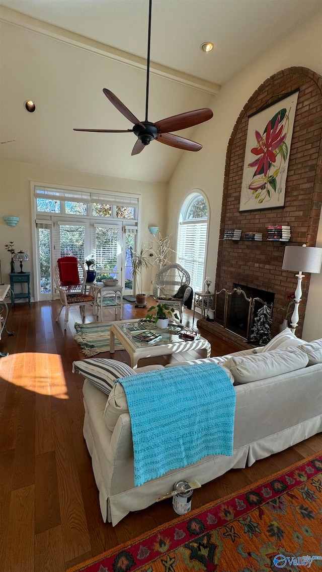 living room with dark wood-type flooring, vaulted ceiling with beams, and a brick fireplace