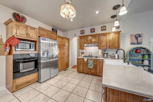 kitchen with light tile patterned floors, appliances with stainless steel finishes, sink, and pendant lighting