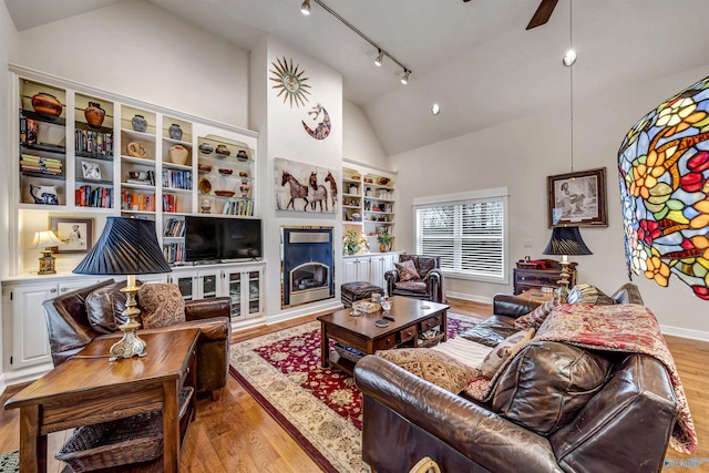 living room with light hardwood / wood-style floors, track lighting, ceiling fan, and vaulted ceiling