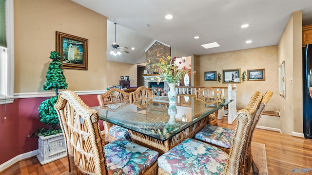 dining room with a fireplace, lofted ceiling, ceiling fan, and light hardwood / wood-style floors