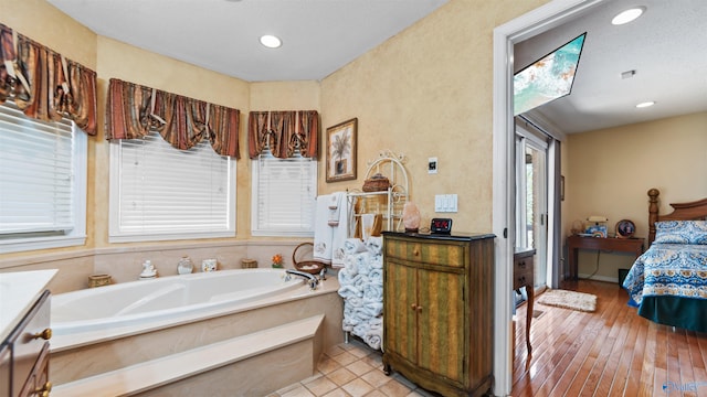 bathroom featuring vanity, a textured ceiling, wood-type flooring, and a bathing tub