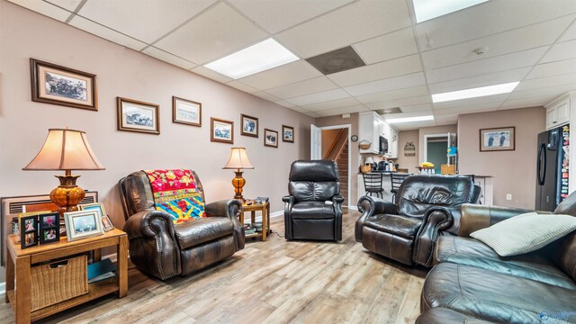 living room with light wood-type flooring and a paneled ceiling