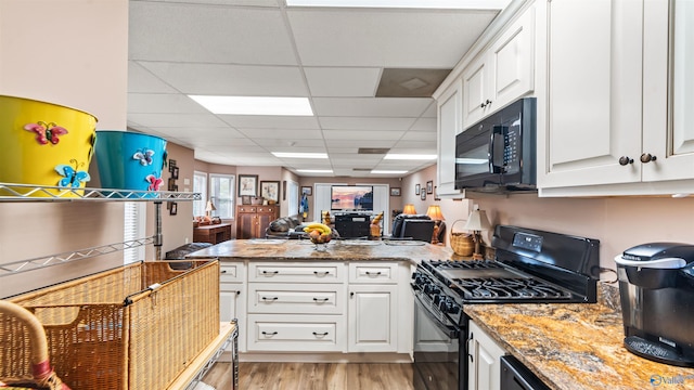 kitchen featuring white cabinetry, black appliances, stone countertops, and light hardwood / wood-style floors