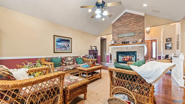 living room with ceiling fan, vaulted ceiling, hardwood / wood-style flooring, and a fireplace