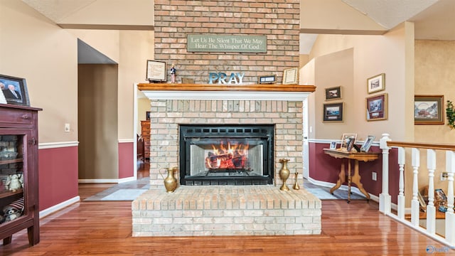 living room featuring lofted ceiling, wood-type flooring, and a brick fireplace