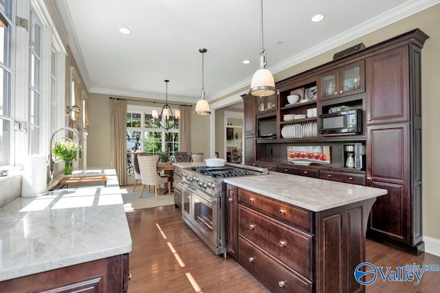 kitchen with dark wood-type flooring, decorative light fixtures, range with two ovens, a kitchen island, and ornamental molding