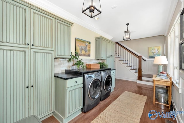 clothes washing area featuring dark hardwood / wood-style flooring, cabinets, washer and dryer, crown molding, and plenty of natural light