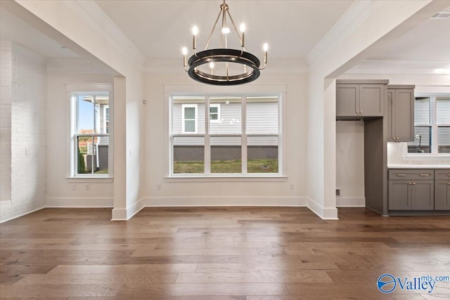 unfurnished dining area featuring dark hardwood / wood-style flooring, crown molding, and a chandelier