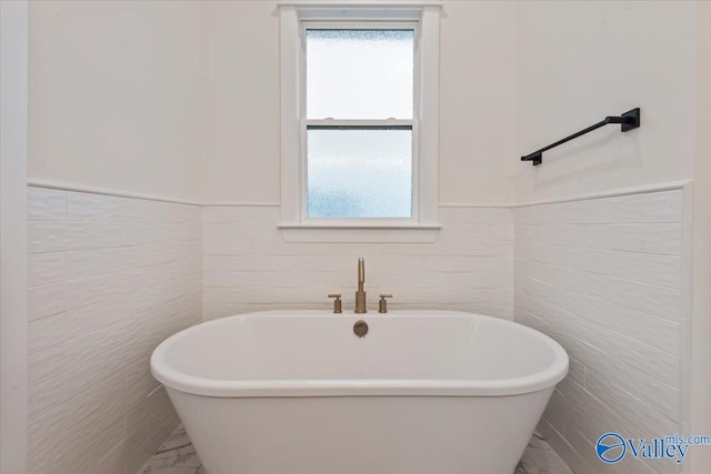 bathroom featuring a washtub and tile walls