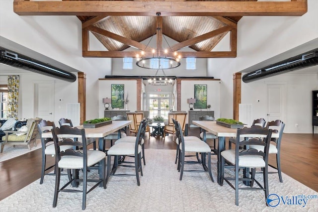 dining room featuring an inviting chandelier, high vaulted ceiling, decorative columns, light hardwood / wood-style floors, and beamed ceiling