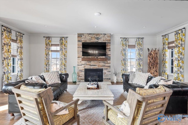 living room featuring ornamental molding, a healthy amount of sunlight, a fireplace, and light hardwood / wood-style floors