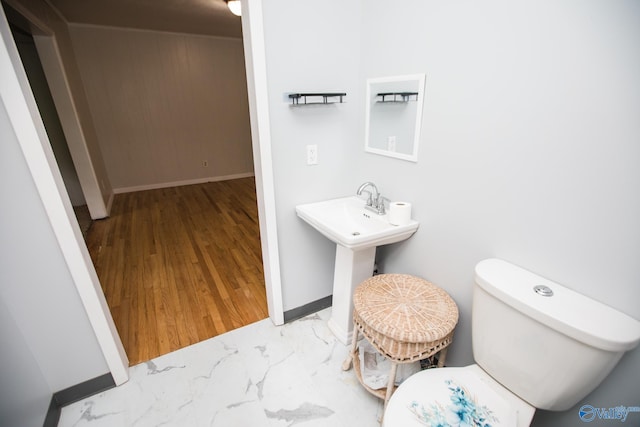 bathroom featuring sink, toilet, and wood walls