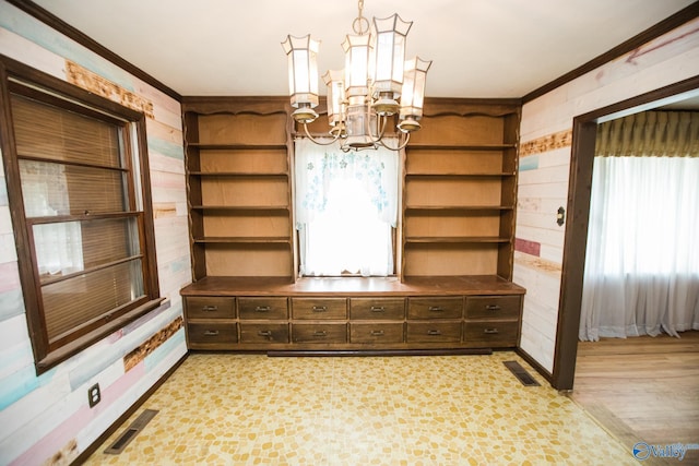 unfurnished dining area with an inviting chandelier, wooden walls, and crown molding