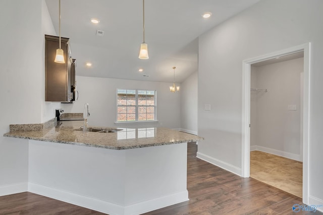 kitchen featuring dark brown cabinetry, light stone countertops, sink, kitchen peninsula, and stove