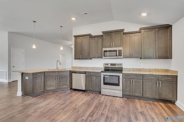 kitchen featuring sink, dark hardwood / wood-style floors, kitchen peninsula, pendant lighting, and appliances with stainless steel finishes