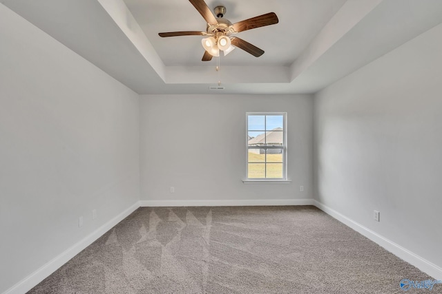 spare room featuring carpet, ceiling fan, and a tray ceiling