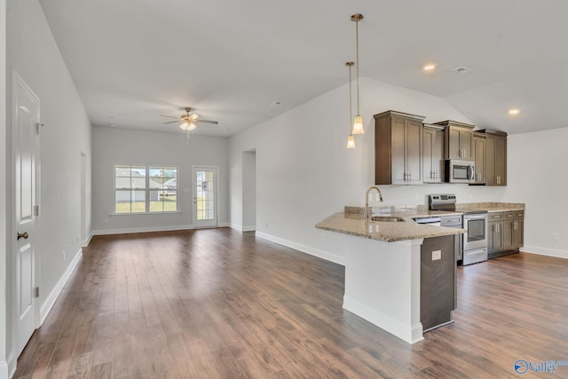 kitchen with pendant lighting, sink, light stone countertops, kitchen peninsula, and stainless steel appliances