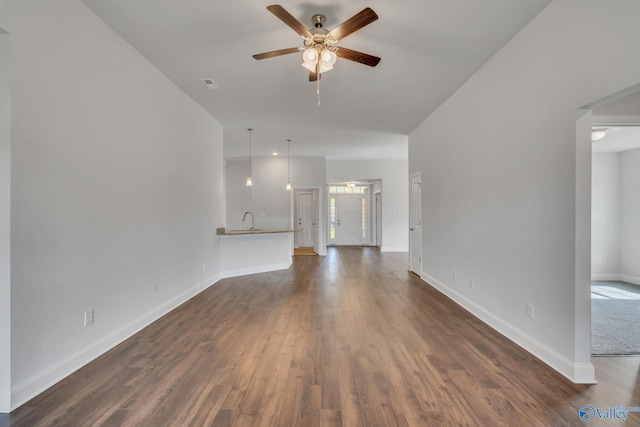 unfurnished living room with dark hardwood / wood-style flooring, ceiling fan, and sink