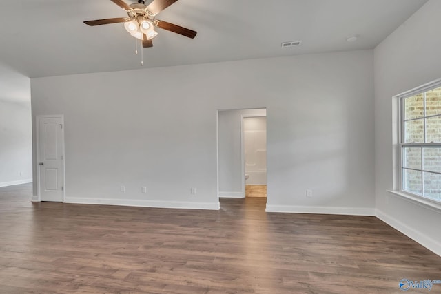 empty room with dark hardwood / wood-style floors, a healthy amount of sunlight, and ceiling fan