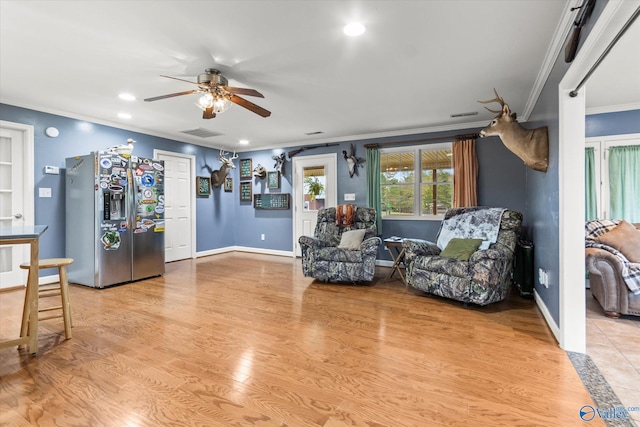 living area featuring light hardwood / wood-style floors, ceiling fan, and crown molding