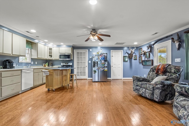 kitchen with a center island, crown molding, ceiling fan, light wood-type flooring, and stainless steel appliances