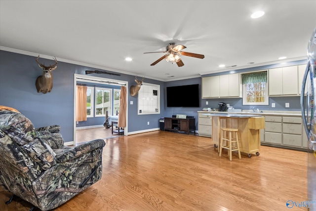 kitchen with white cabinets, a center island, light hardwood / wood-style floors, and a breakfast bar
