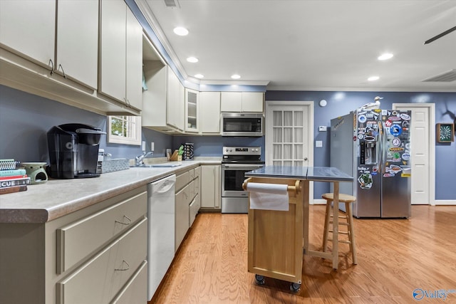 kitchen featuring appliances with stainless steel finishes, light hardwood / wood-style flooring, a center island, white cabinetry, and a breakfast bar area