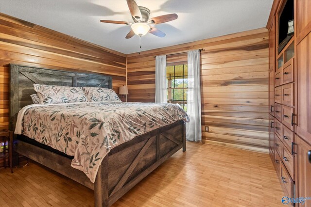 bedroom featuring light wood-type flooring, ceiling fan, and wood walls