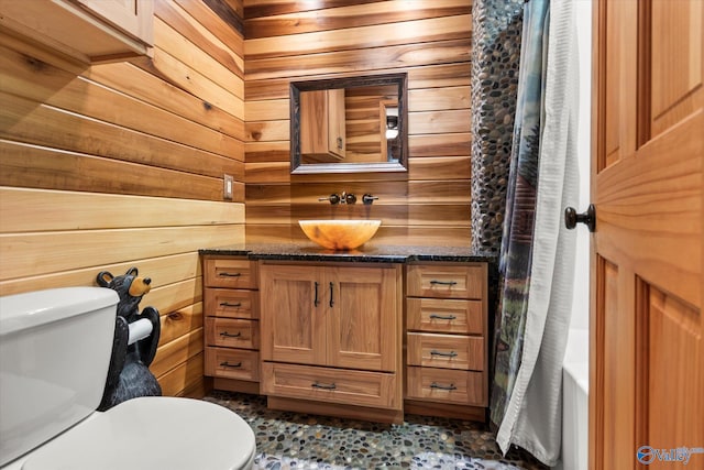 bathroom featuring wooden walls, tile patterned flooring, vanity, and toilet